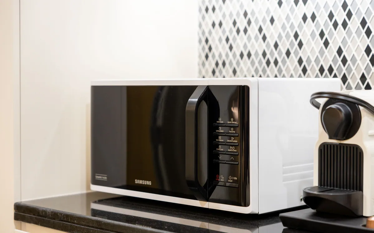 A countertop microwave beside a compact coffee maker.