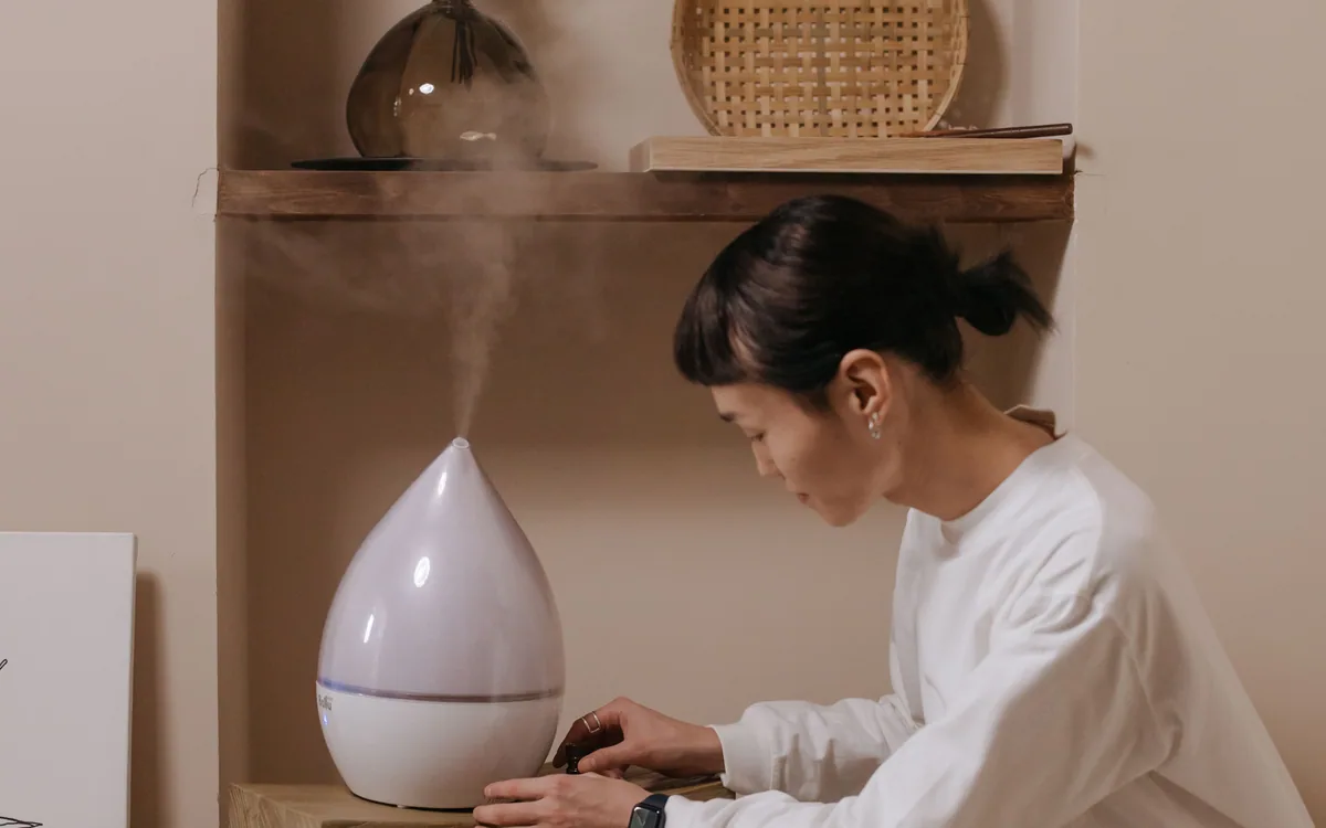 A person adjusting a humidifier indoors.