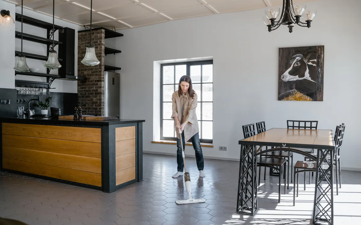 A person mopping the floor in a bright kitchen.