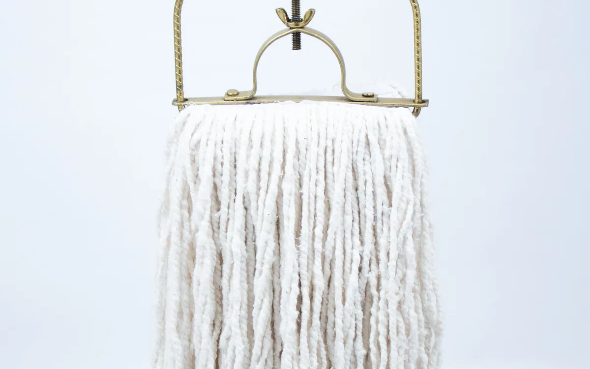 A white string-mop head with a metal clamp.