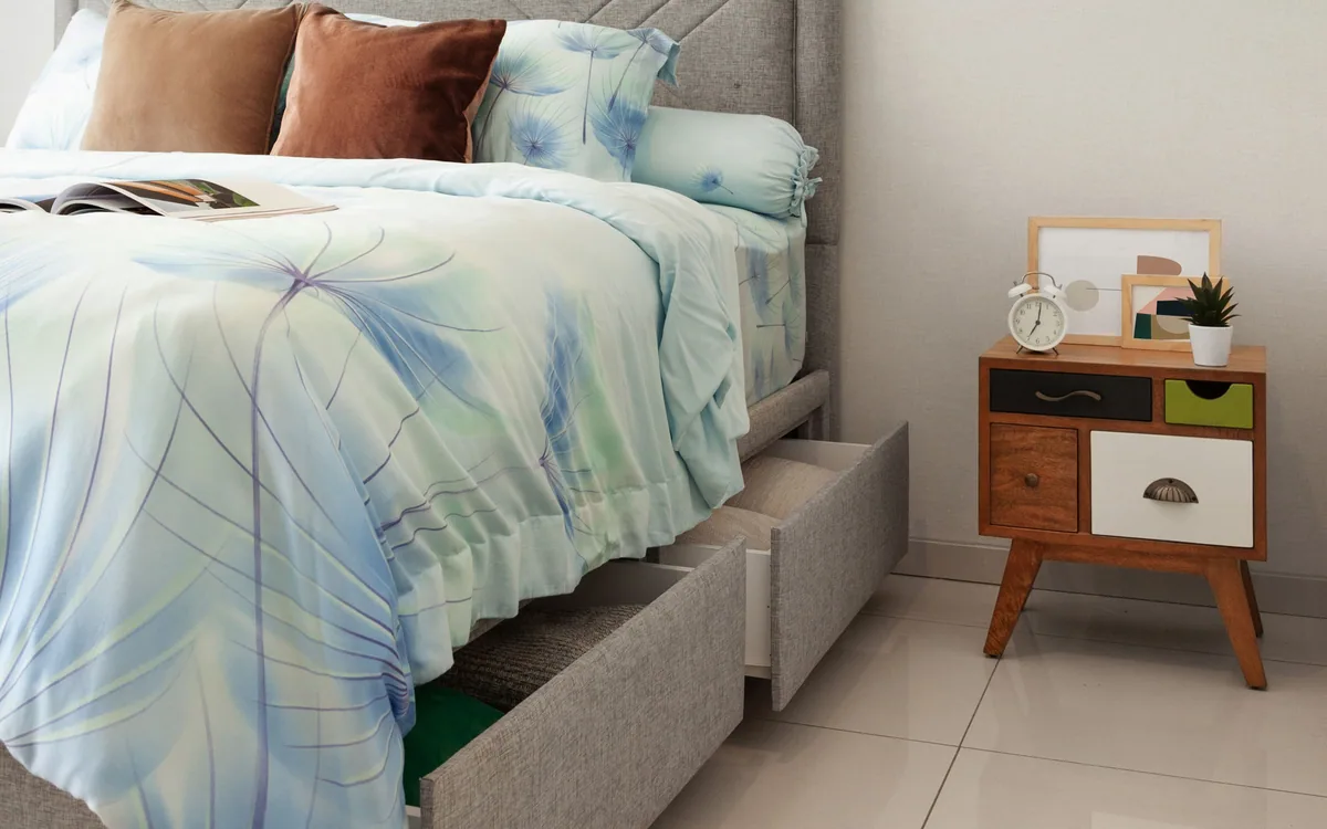 A bed with integrated drawers beside a bedside table.