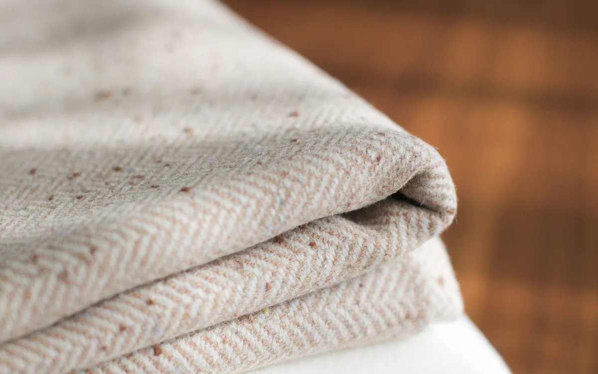Folded neutral-colored linens stacked on a wood surface.