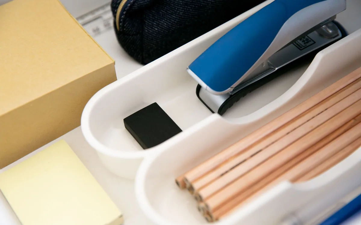 An open desk drawer divided into spaces for office supplies.