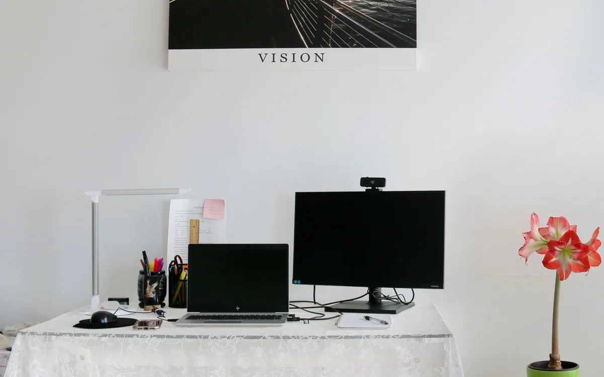 A laptop and external monitor with a webcam in a home workspace.