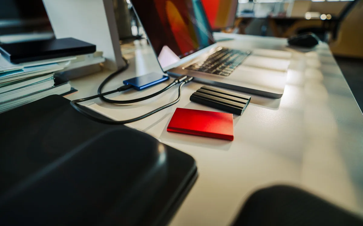 External storage drives beside a laptop on an office desk.