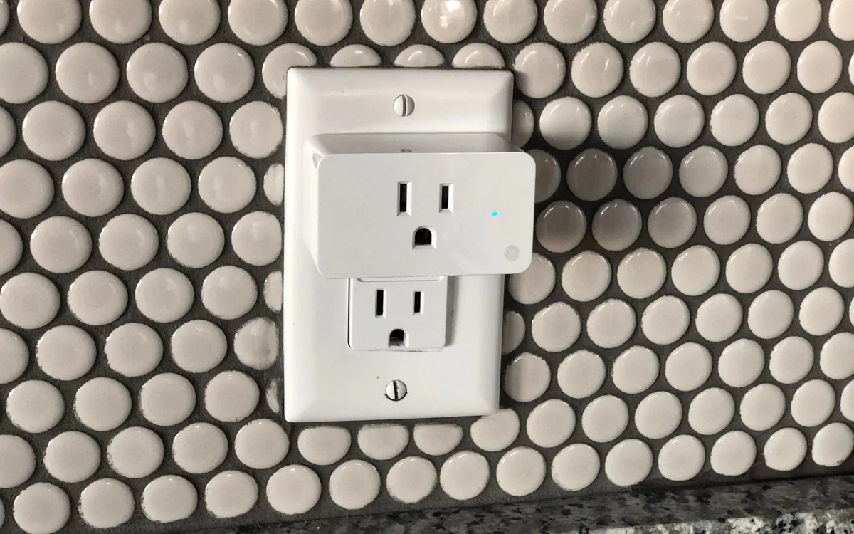 A plug-in smart socket mounted on a tiled wall.