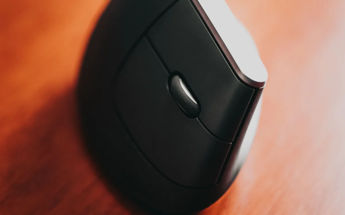 A wireless computer mouse on a wooden desktop.
