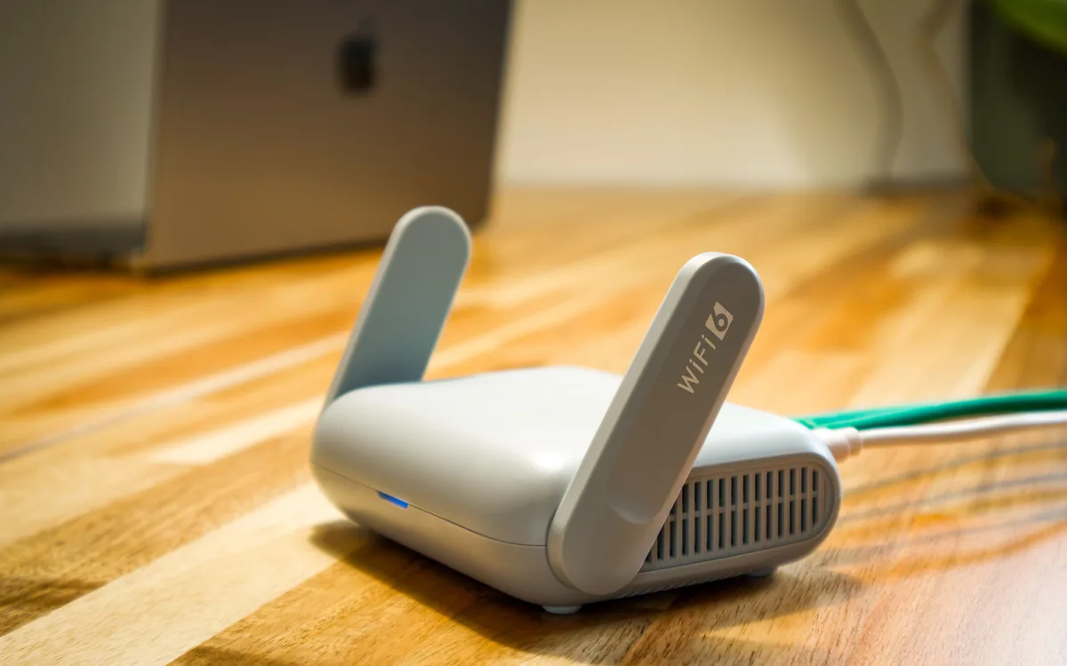 A wireless router and connected cable on a wooden desk.