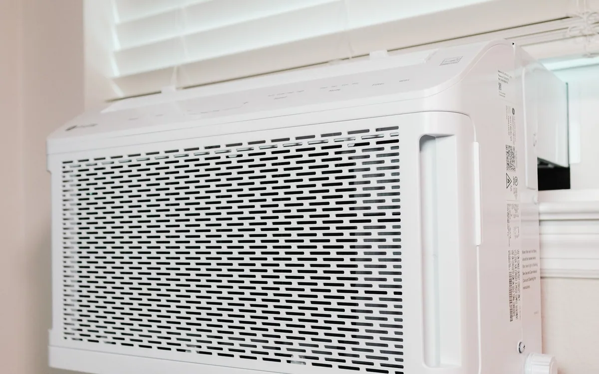 A window air conditioner beneath blinds in a home.