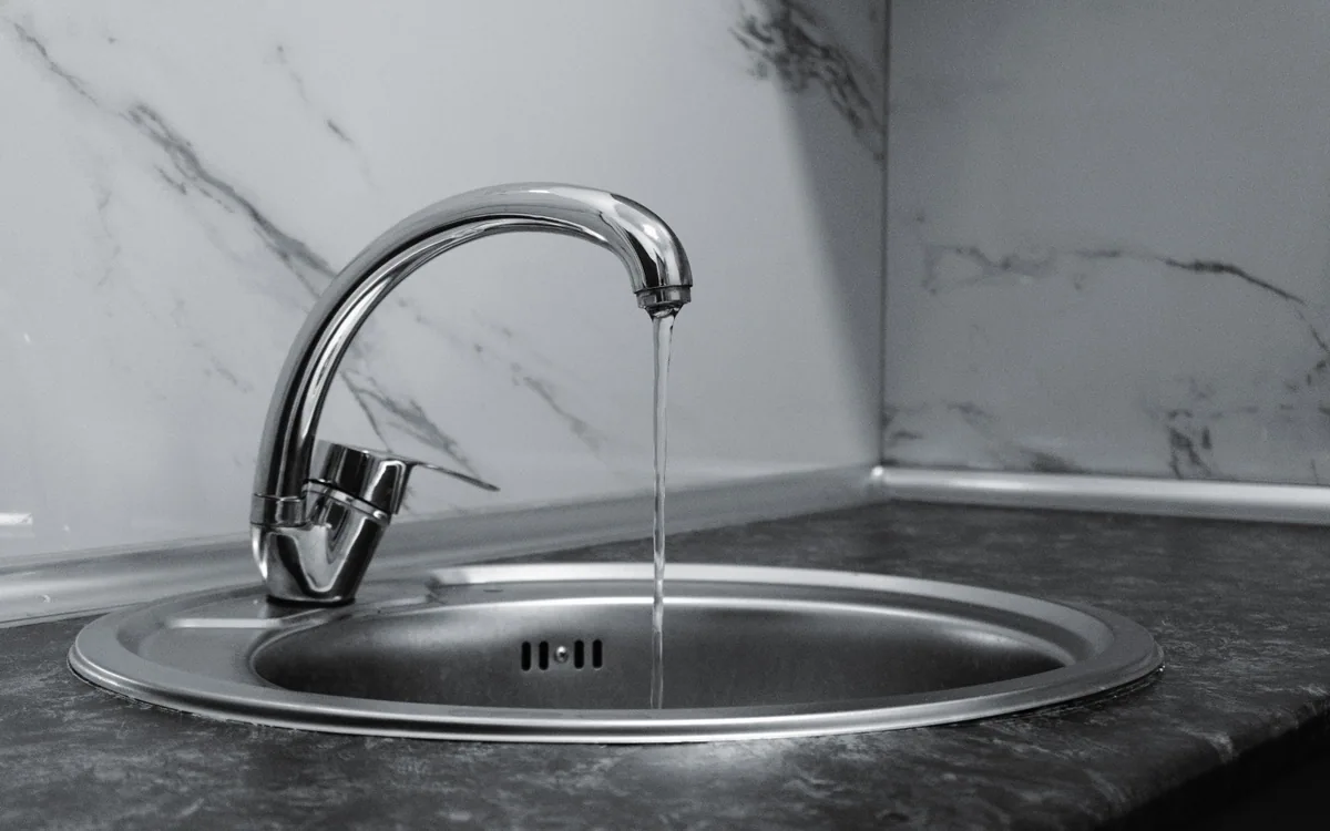 Water running from a chrome kitchen faucet.