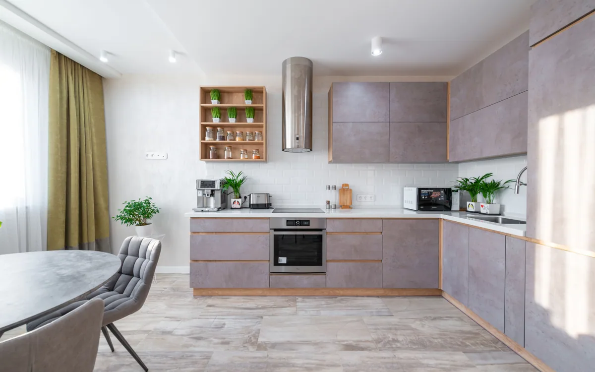 A sunlit apartment kitchen with a dining area and open workspace.